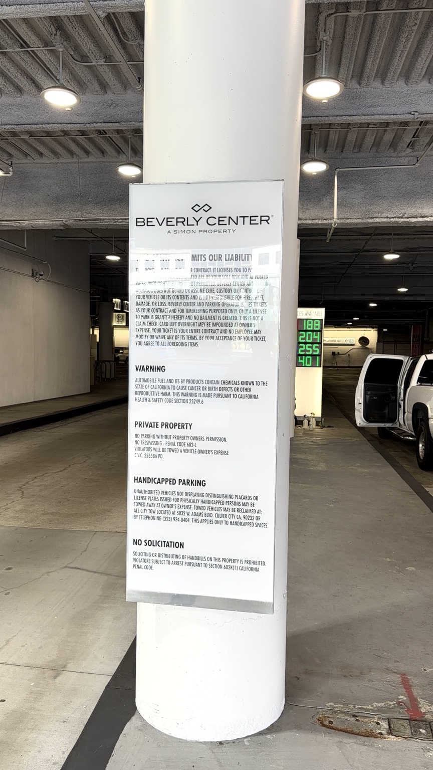 Tall Beverly Center parking liability and property-information sign mounted on a white garage column