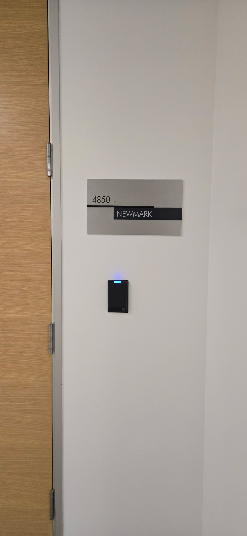 Gray suite sign with room number 4850 and a black Newmark tenant-name panel beside an office door